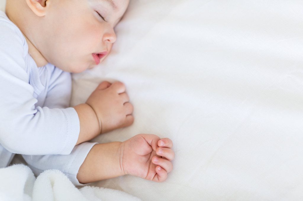 baby snoring in bed dressed in romper